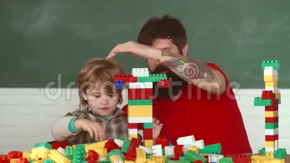 带着橙色头盔或头盔的幼儿帮助他留胡子的父亲小孩和他父亲一起建房子视频的预览图