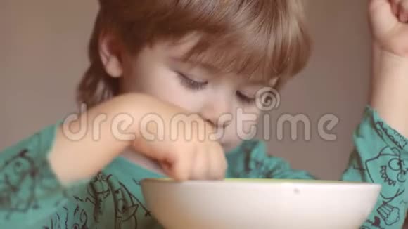 快乐的婴儿用勺子吃食物可爱的笑着的小男孩的肖像金发视频的预览图