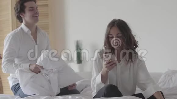 快乐无忧无虑的男人和女人在床上玩快乐枕头在家里享受有趣的休闲活动视频的预览图