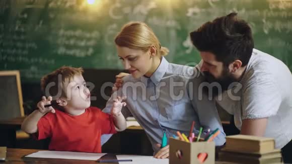 家人在做快乐的活动父母在教画画孩子男人女人和男孩在学校班画画视频的预览图