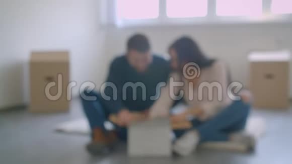 年轻的白种人夫妇坐在新房子的地板上解开照片变得快乐和兴奋视频的预览图