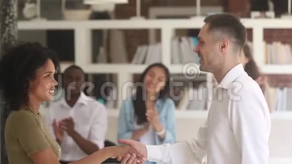 高加索男经理老师握手赞美快乐的非洲女员工视频的预览图