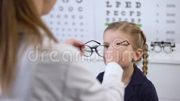 女医生戴眼镜在快乐的孩子时尚眼镜在光学商店视频的预览图