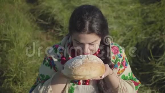可爱的超重女人坐在草地上嗅着美味的面包准备吃的肖像传统观念国家视频的预览图
