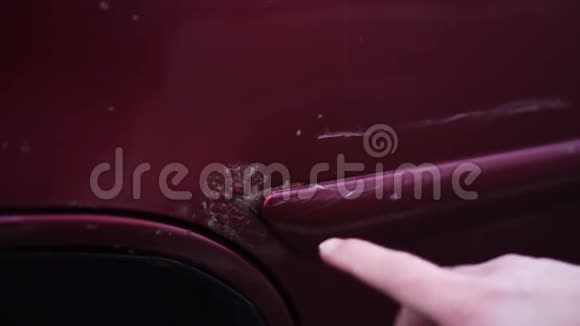 人在汽车油漆中表现出铁锈手指指向红色汽车的划痕视频的预览图