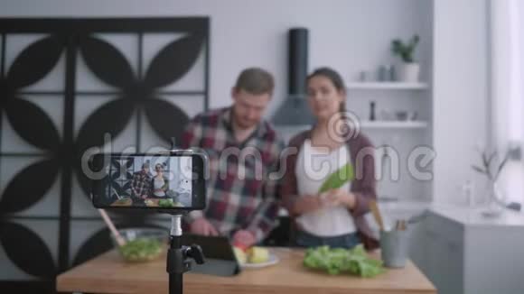 减肥博客vloggers男性和女性准备健康的早午餐配蔬菜和蔬菜手机视频的预览图