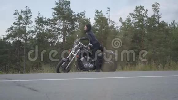 白人女孩坐在摩托车上戴着头盔和手套穿着黑色皮夹克骑着一辆视频的预览图