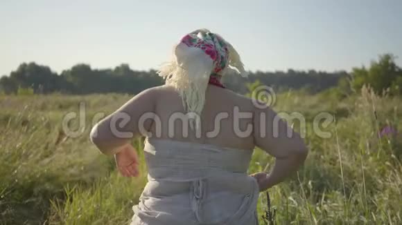 背部观看超重妇女脱下披肩解开头发和跑步在夏季的田野女人逃离视频的预览图