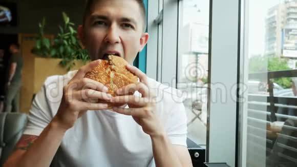 年轻帅哥在快餐店吃汉堡视频的预览图