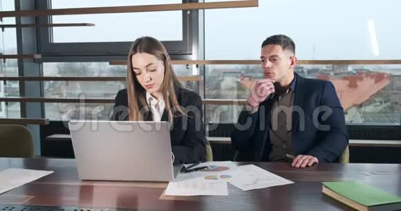 体贴的男人看到女人是如何在明亮的现代办公室工作的有关女性的笔记本电脑工作商务视频的预览图