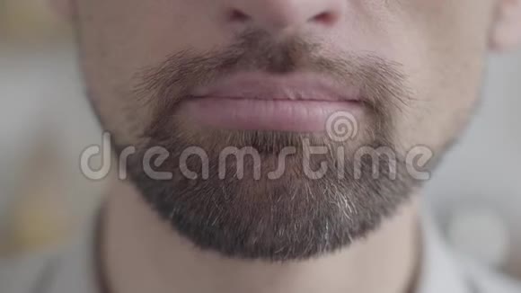 一个满脸胡须的成年男子的下颚特写试图用强迫的微笑微笑消极情绪问题视频的预览图