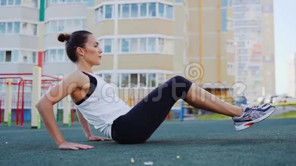 运动女性在新鲜空气中对腹肌进行锻炼那个女孩在街上参加体育活动视频的预览图