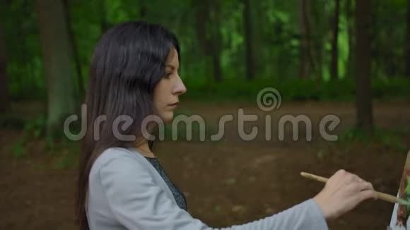 一个女孩在森林里画风景的侧视视频的预览图