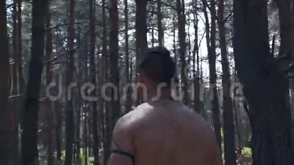 野蛮的战士赤裸的躯干手里拿着两把斧头在树林里行走视频的预览图