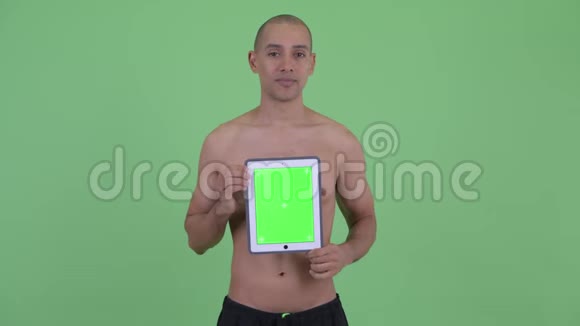 快乐秃顶多民族赤膊男子一边思考一边展示数码平板电脑视频的预览图