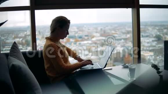 有城市景观的咖啡馆里面有一台笔记本电脑的女人视频的预览图