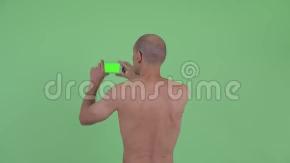 秃顶多民族赤膊男子用电话拍照后景视频的预览图