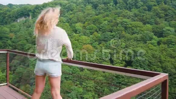 美丽的成年少女金发碧眼的长发披在深渊上的铁桥上美丽的野生动物中的女士视频的预览图