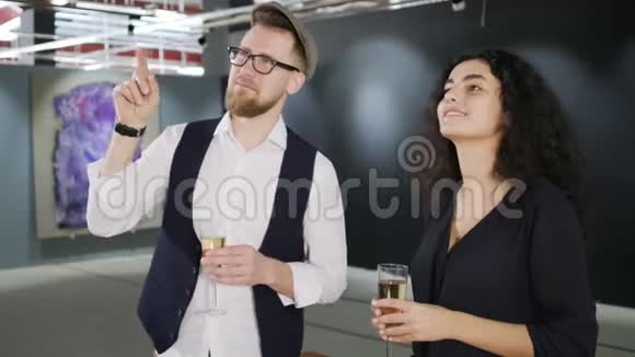男人和女人在打开画廊和观看照片时都在喝香槟视频的预览图