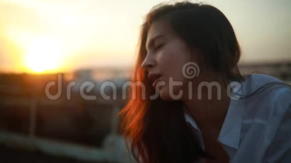 女人披散头发闭着眼睛在夕阳下唱着歌视频的预览图