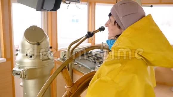 穿着黄色雨衣的老妇人控制着掌舵的船视频的预览图