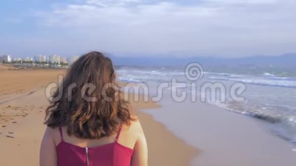 一个夏天穿红衣服的女孩在海滩上散步视频的预览图