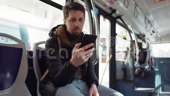 男人正在乘坐公共汽车看着智能手机的屏幕视频的预览图