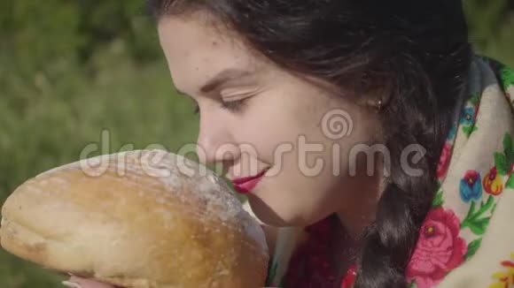 一幅美丽丰满的女人坐在草地上嗅着美味的面包准备吃的肖像传统观念联系视频的预览图