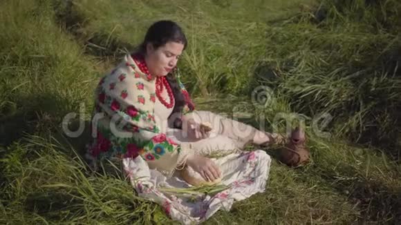 美丽的超重女人坐在草地上吃着新鲜的面包和黄瓜传统视频的预览图