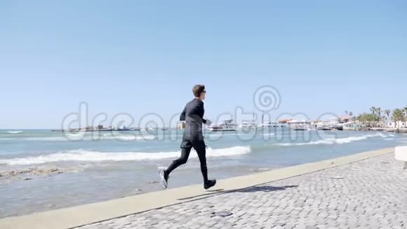 年轻迷人的白种人穿着黑色衣服在码头上奔跑后退慢镜头视频的预览图
