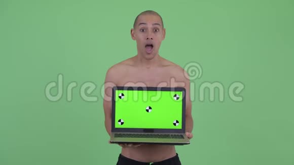 快乐的秃头多民族赤膊男子展示笔记本电脑看上去很惊讶视频的预览图