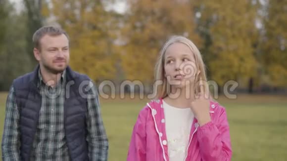 白种人父亲和他的金发女儿在秋天公园拥抱的肖像一家人看着摄像机视频的预览图