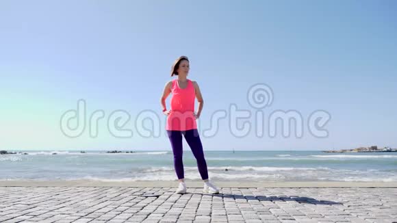 年轻迷人的白种人女人在海滩码头上玩着手在空中跳跃的乐趣慢动作视频的预览图