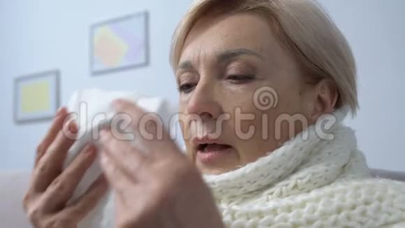 戴围巾的老年女士打喷嚏看组织流感病毒季节性流行治疗视频的预览图