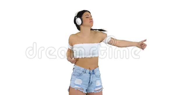 白人女性模特戴着耳机跳跃在白色背景下表达着听音乐的快乐情绪视频的预览图