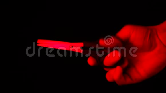 手里拿着剪刀用红色的光隔开黑色的背景视频的预览图