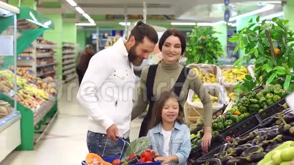 一个年轻的家庭有一个可爱的女儿在超市买蔬菜视频的预览图