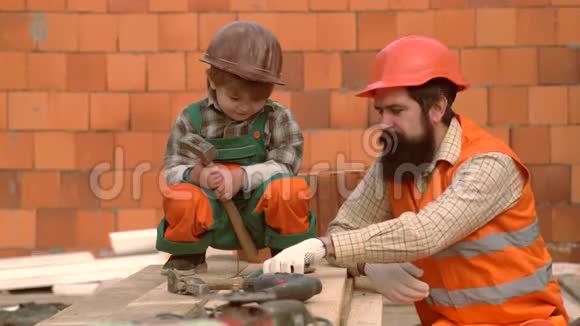 儿子和父亲放一块砖来建一堵墙使用工具小儿子帮他父亲做建筑工作男孩游戏视频的预览图