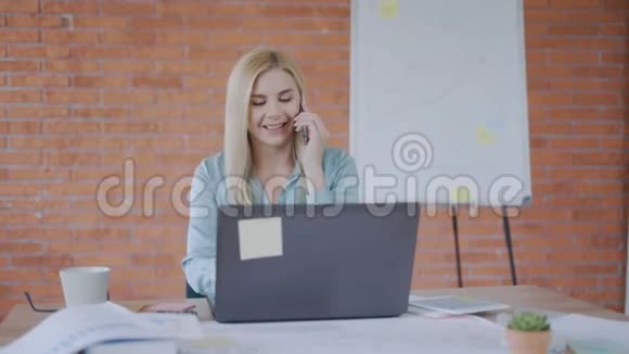 成功的商务女性在她自己的办公室里一边坐在桌子旁一边打电话成功的概念4K视频的预览图