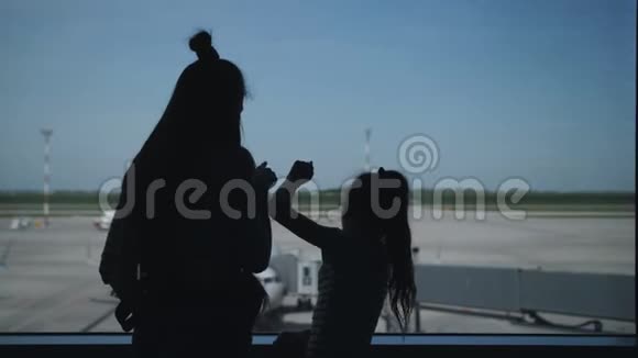 机场大厅里两姐妹的剪影站在窗口看着跑道上的飞机视频的预览图