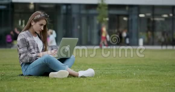 女孩用笔记本电脑在互联网上查找信息一个漂亮的女大学生坐在阴凉处视频的预览图