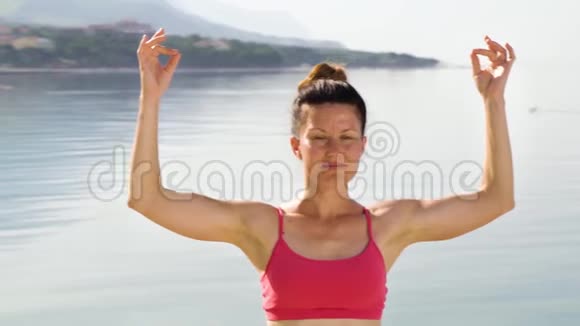 女子练习瑜伽的弧线镜头在海边用泥做手势保持手指视频的预览图