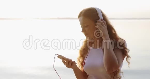 肖像红头雀斑的女孩戴着白色耳机正在听歌和微笑视频的预览图