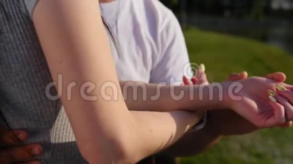 当幸福的一对夫妇站在公园附近时一年轻男子牵着一位年轻女子的手的浪漫特写视频的预览图