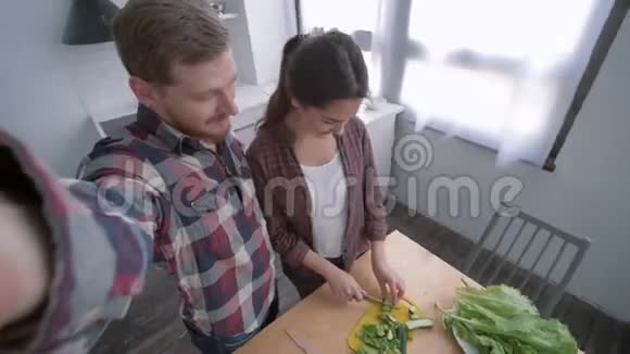 快乐的女孩与男人在手机上自拍照片而烹饪蔬菜沙拉在晚餐健康视频的预览图