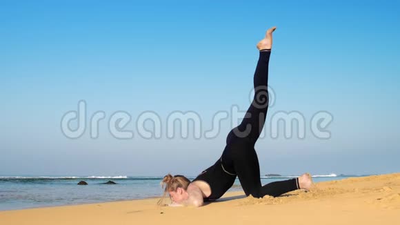 年轻女子在无尽的蓝色海洋中以瑜伽姿势举起腿视频的预览图