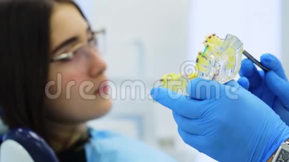 牙医的手与下巴模型显示给女孩如何安装牙套视频的预览图