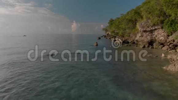 在靠近岩石海岸的清水上缓慢低空飞行电影观视频的预览图