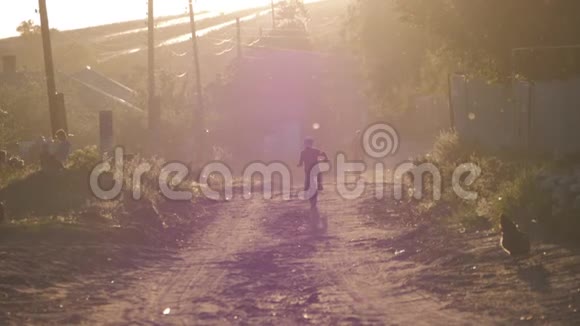 男孩骑着自行车在夕阳下沿着村庄的道路视频的预览图