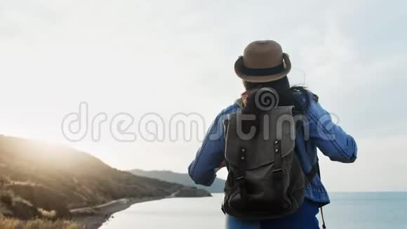 后景活动背包客女性走近大海欣赏山上迷人的海景视频的预览图